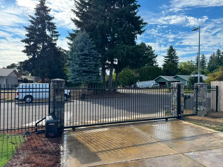 Black iron cantilever slide gate with LiftMaster operator and stone columns, street setting