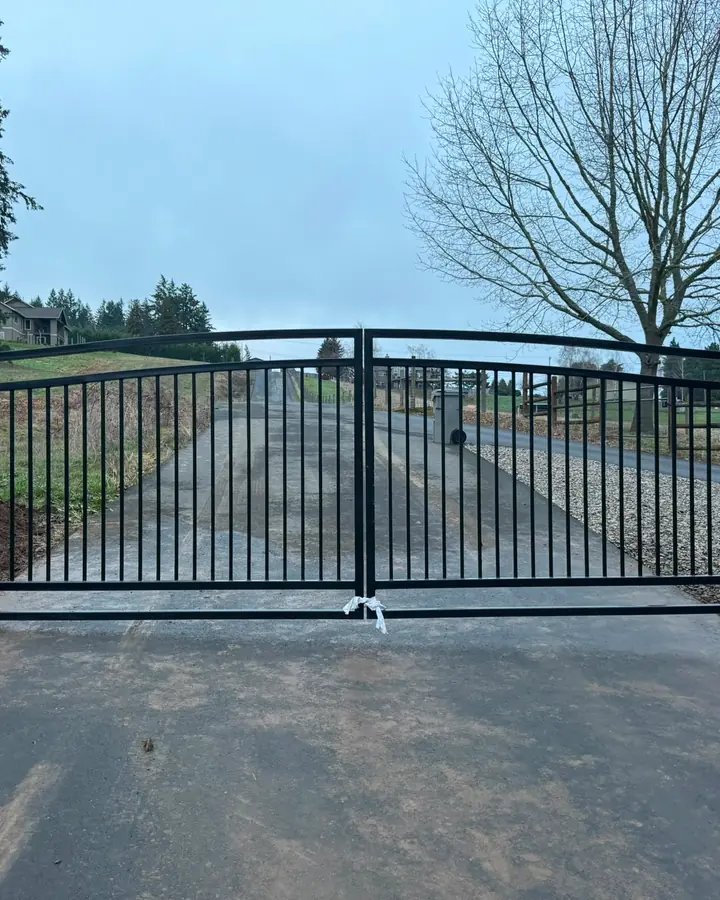 Finished black metal arched double swing driveway gate closed, wide frontal view — Interstate Gate Repair