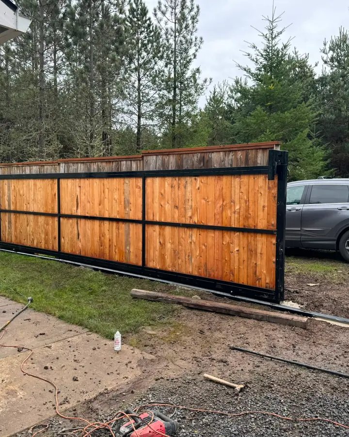 Sliding cedar gate rolled open mid-install with worker and SUV in driveway — Interstate Gate Repair