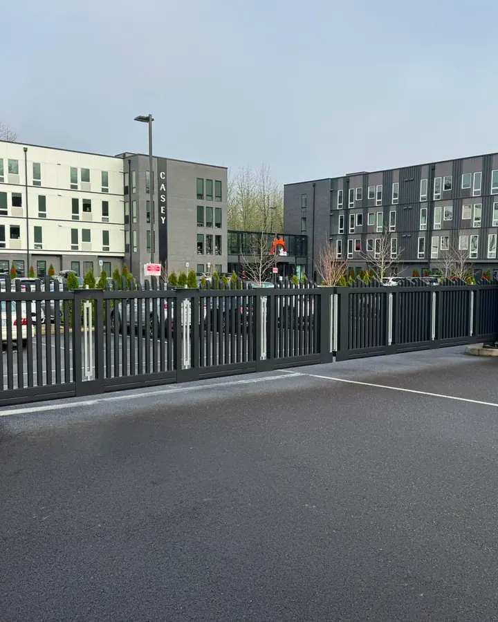 Dark metal sliding security gate at apartment complex parking lot entrance — Interstate Gate Repair