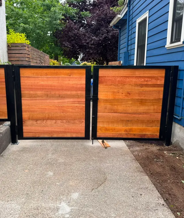 Finished horizontal cedar gates with black steel frames across driveway — Interstate Gate Repair