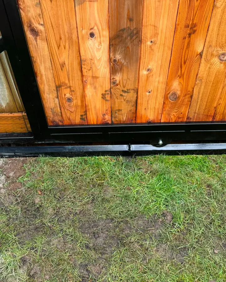 Detail of bottom corner of cedar gate showing steel frame and roller — Interstate Gate Repair