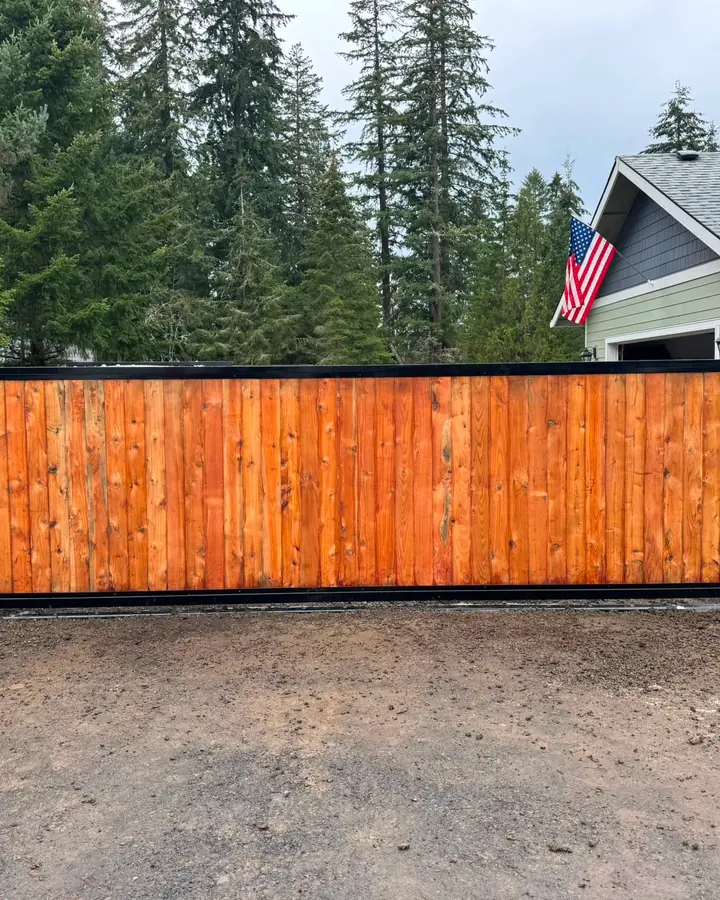 Finished cedar sliding driveway gate front view with US flag and home — Interstate Gate Repair