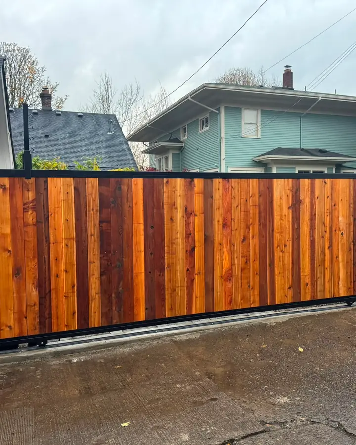 Finished cedar-clad steel-frame sliding driveway gate in alley with keypad — Interstate Gate Repair