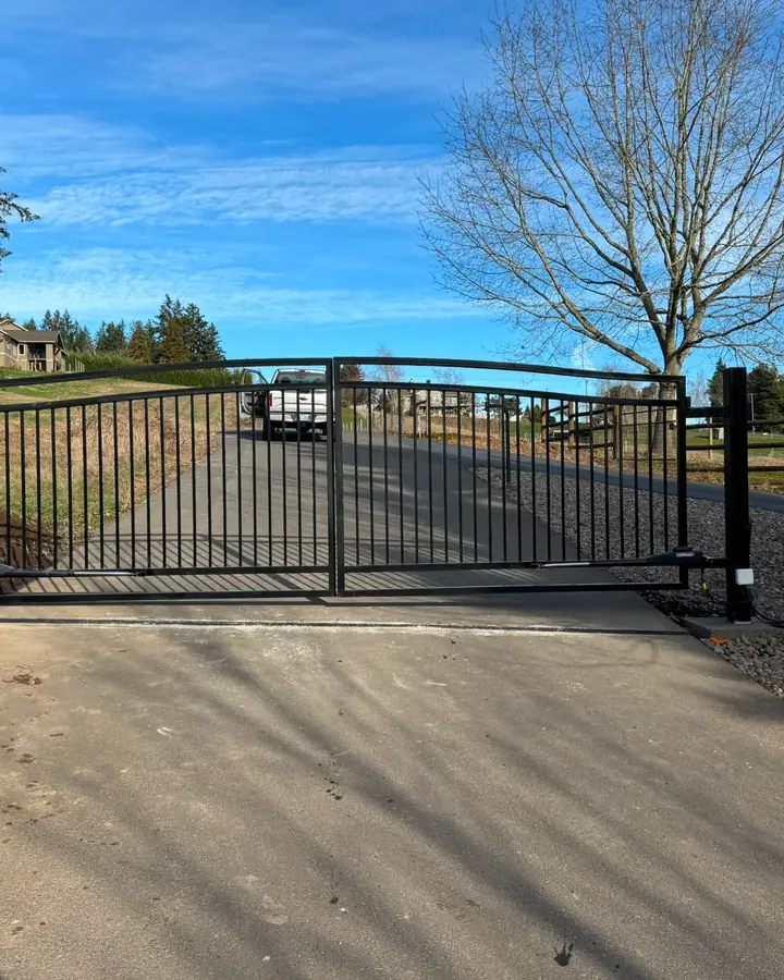 Closed black steel dual-swing driveway gate with LiftMaster operators on concrete apron — Interstate Gate Repair