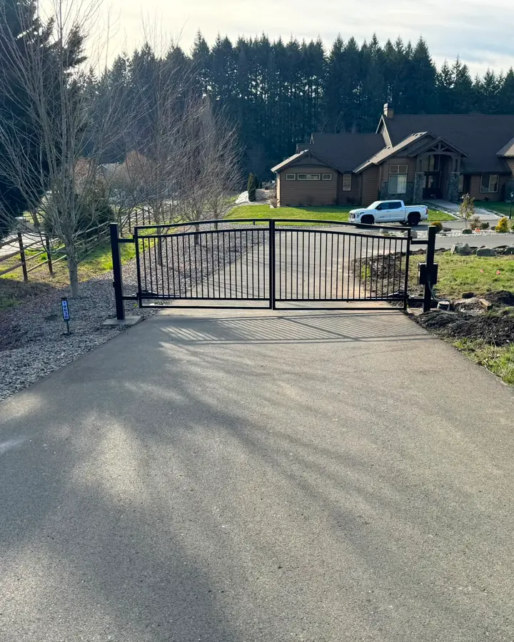 Closed arched black metal driveway gate viewed from road, craftsman estate beyond — Interstate Gate Repair