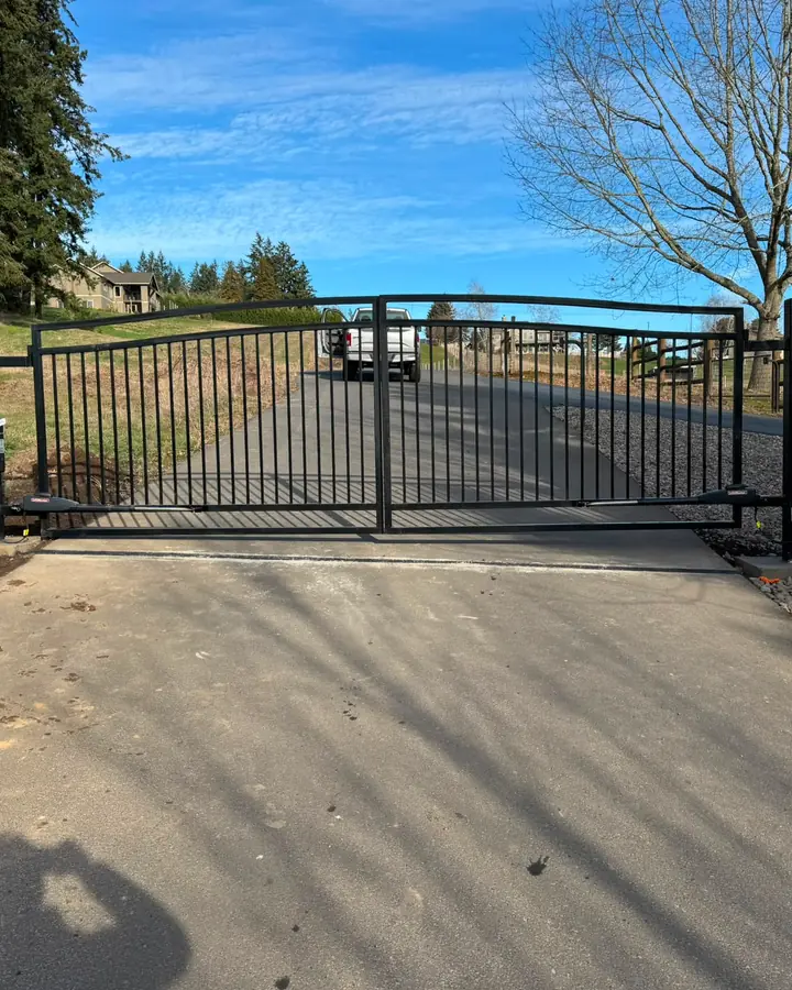 Closed arched dual-swing driveway gate with LiftMaster arm operators on concrete pad — Interstate Gate Repair