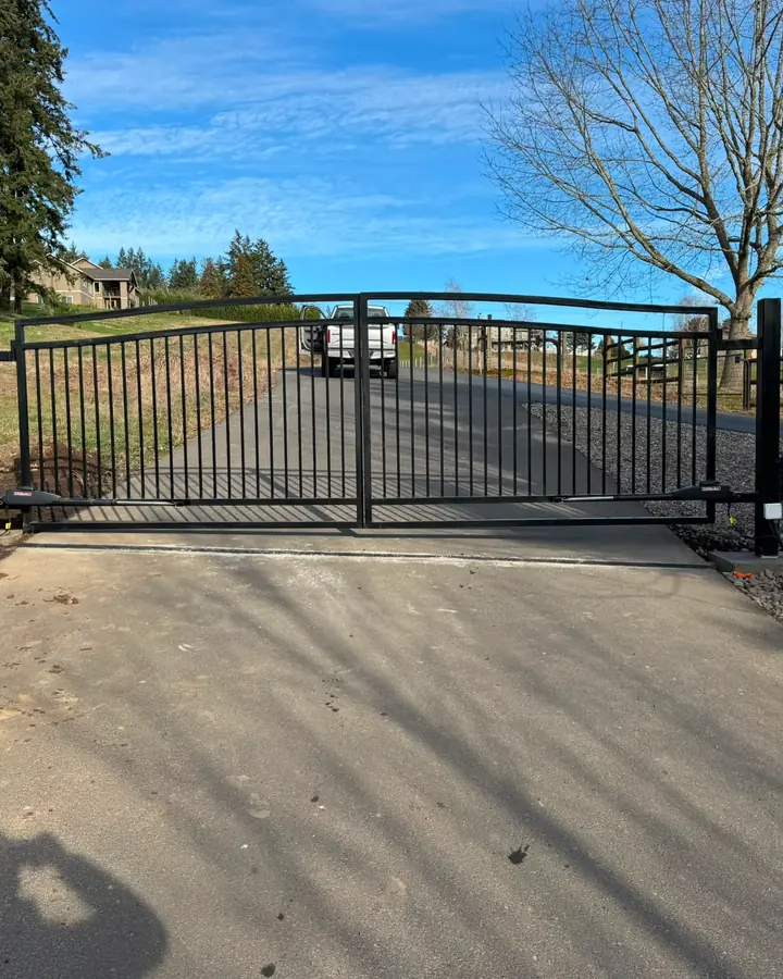 Closed arched dual-swing driveway gate with LiftMaster operators, sunny rural drive — Interstate Gate Repair