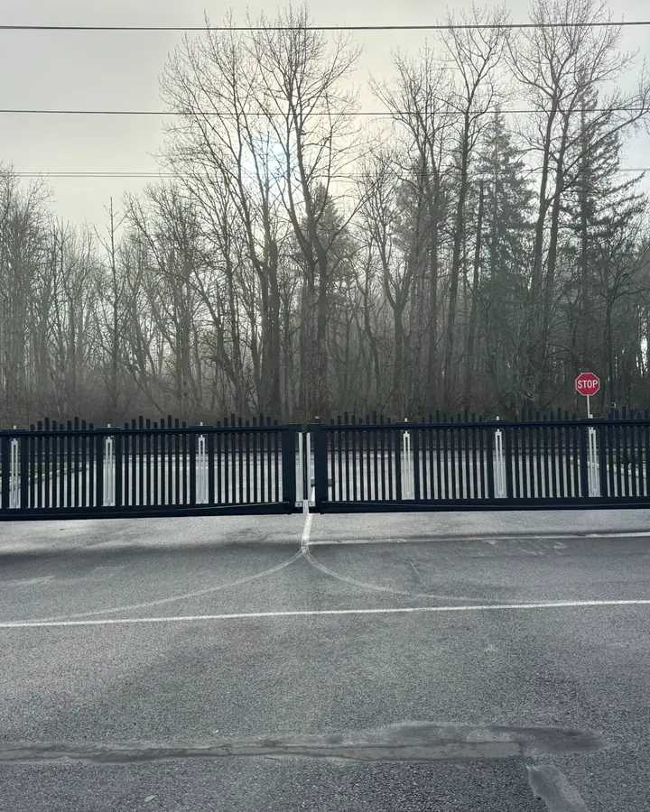 Black cantilever bi-parting slide gate with HySecurity operators at wooded lot — Interstate Gate Repair