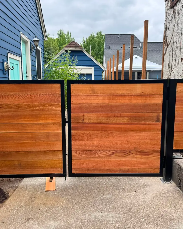 Horizontal cedar wood swing gates with black steel frames between houses — Interstate Gate Repair