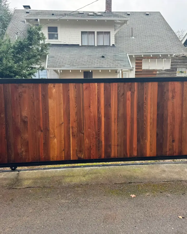 Completed cedar slide gate with steel frame on residential alley, houses behind — Interstate Gate Repair