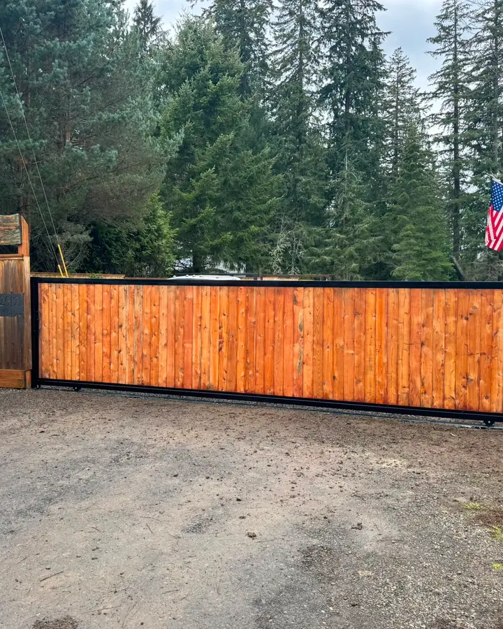 Completed cedar rolling gate at rural driveway entrance with property sign — Interstate Gate Repair