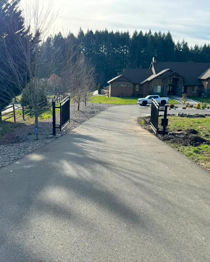Open black metal dual-swing driveway gate with automation, craftsman home beyond — Interstate Gate Repair
