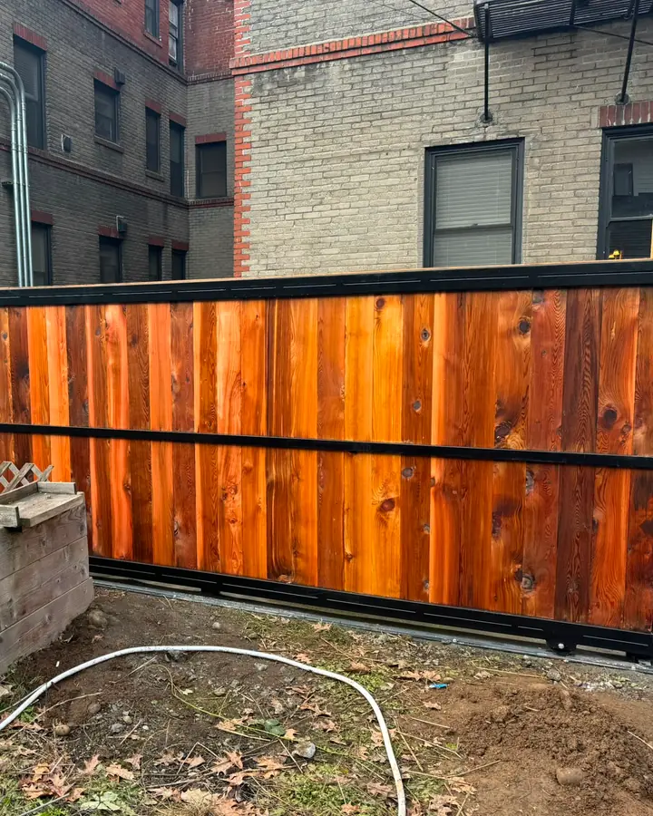 Wide view of cedar slide gate in black frame beside lattice and cedar fence — Interstate Gate Repair