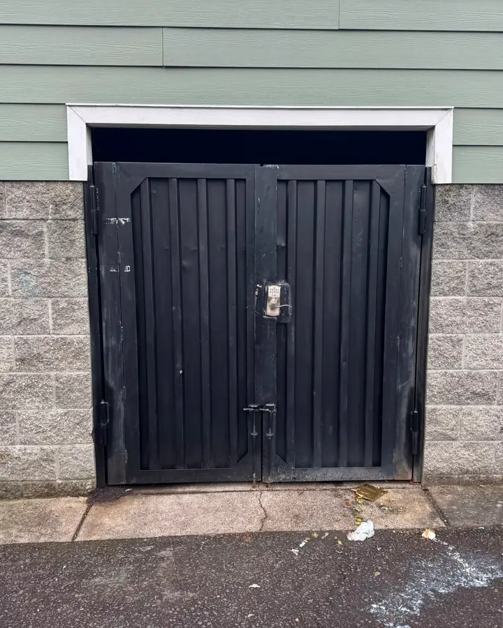 Black steel double swing gate with keypad in block wall opening, some wear — Interstate Gate Repair