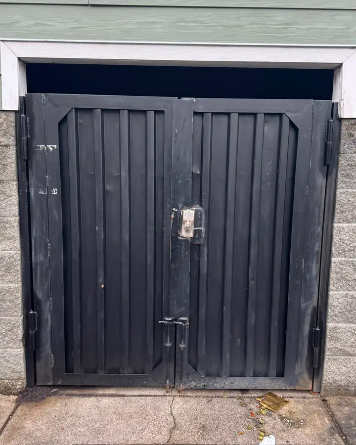 Weathered black steel double swing gate with keypad and cane bolts in block wall — Interstate Gate Repair